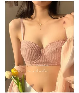 Detail of pink lace bra with waffle texture and thin shoulder straps shown on a model