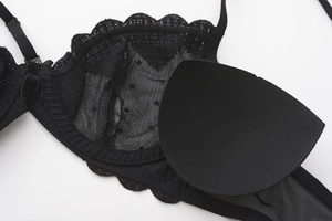 Detail view of the black lace bra showing the removable crescent-shaped breast pads and mesh