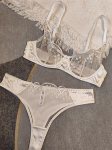 Flat lay of creamy lace lingerie set with polka dot embroidery and satin detailing