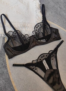 Détail d'un ensemble de lingerie en résille à pois noirs et textures de satin