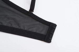 Detail of black mesh bra back featuring adjustable straps and triple hook-and-eye closure