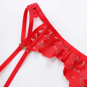 Détail d'un porte-jarretelles en dentelle rouge avec motifs floraux et boucles dorées