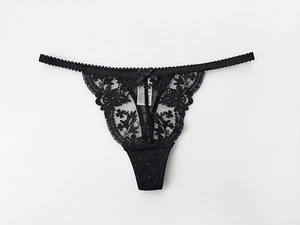 Detail of black lace G-string featuring delicate polka dot mesh and center bow ornament