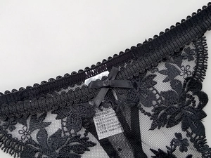 Detail of black lace panties with delicate floral embroidery and a satin bow