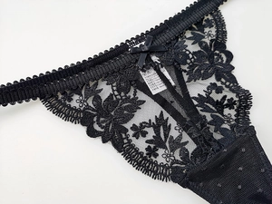 Detailed macro view of black floral eyelash lace and decorative bow on thong underwear