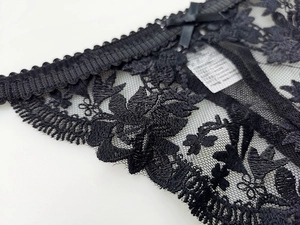 Detail of floral lace mesh underwear with a black satin bow and scalloped edge