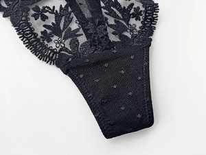 Detail of delicate floral eyelash lace and sheer mesh fabric on black thong underwear