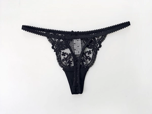 Detailed close-up of black floral lace embroidery and scallop edge on low-rise thong