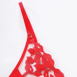 Détail de soutien-gorge en résille rouge avec broderie lèvres et anneau de réglage doré