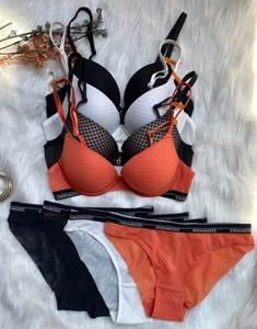 Flat lay of letter print lingerie sets in orange white and black on faux fur background