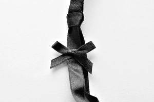 Detail of a black satin bow with fine horizontal texture on a lace lingerie piece