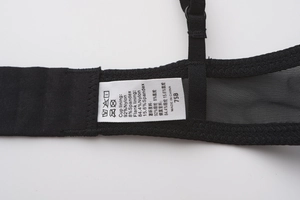 Detailed view of black lace bra wing showing material labels and stitching quality