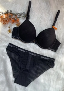 Detailed flat lay of black textured lingerie set with logo waistbands on plush white faux fur