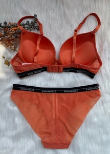 Flat lay of an orange lace lingerie set with 3/4 cups and branded elastic waistband