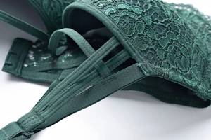Dettaglio del reggiseno in pizzo verde scuro con ricami raffinati e spalline multiple