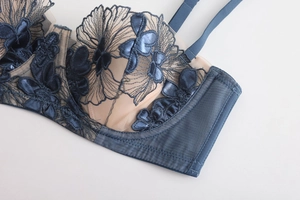 Close-up of intricate navy blue floral embroidery on sheer mesh cups of a lace bra
