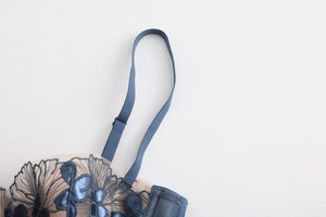 Detail of dark blue floral embroidery and adjustable strap on a French style lace bra