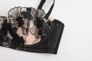 Detailed view of black floral embroidery and eyelash lace on a sheer beige bra cup