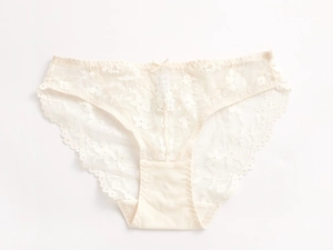 Vue détaillée de la culotte en dentelle florale beige avec bords festonnés et petit noeud