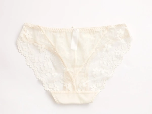 Détails de la dentelle florale et du mesh respirant sur cette culotte basse crème