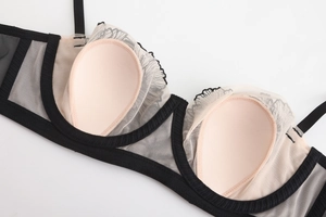 Detail of sheer black lace bra showing mesh fabric and built-in skin-tone pads
