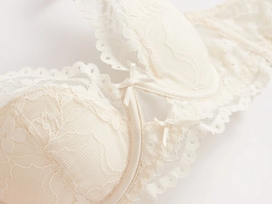 Gros plan d'un soutien-gorge en dentelle crème avec bords festonnés et petit nœud