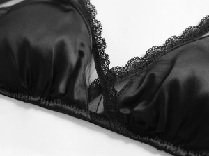 Detailed macro view of black satin fabric with delicate lace and mesh paneling on bra