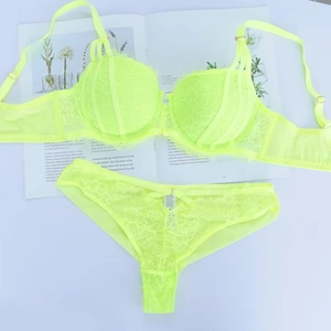 Dettaglio completo di set lingerie in pizzo giallo fluo con finiture metalliche dorate