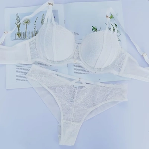 Dettaglio di un set di lingerie in pizzo bianco con rete floreale e fibbie dorate