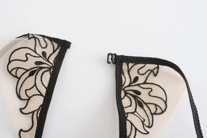 Close-up of floral lace embroidery on beige mesh fabric with a black hook fastener
