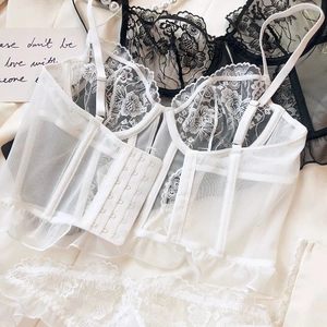 Close-up of white lace bustier with floral embroidery, corset bones and mesh details