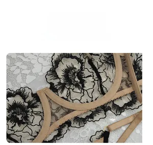 Dettaglio di ricamo floreale nero su mesh velato con finiture in metallo oro