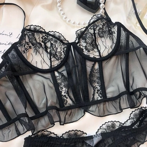 Flat lay of black floral lace bustier and mesh panties with elegant pearl accessories