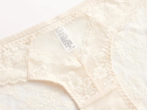 Detailed close-up of cream floral lace and mesh texture on women's underwear with M size tag
