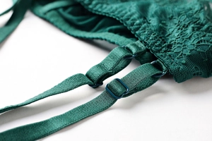 Detail of dark green lace bra showing floral patterns and smooth satin straps