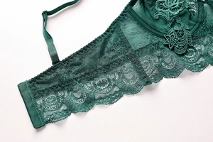 Close-up of deep green lace bra showing intricate floral embroidery and sheer mesh detail