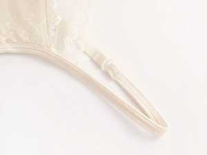 Close-up of adjustable strap buckle and scalloped lace edge on beige French style bra