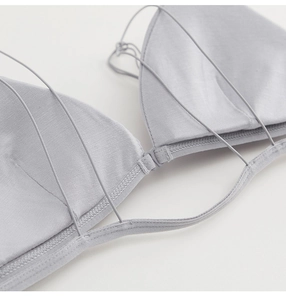 Close-up of light grey bralette featuring delicate cross-back straps and front clasp closure