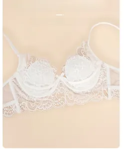 Détail d'un soutien-gorge en dentelle blanche avec broderie florale et petit nœud