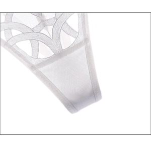 Close-up of white lace thong featuring geometric embroidery and breathable mesh texture