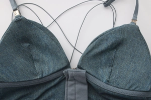 Dettaglio ravvicinato del reggiseno in denim blu con fibbie in metallo dorato sui cinturini