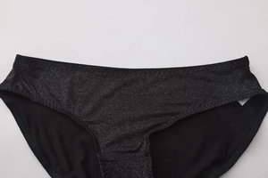 Dettaglio ravvicinato di slip neri glitterati con texture lucida e bordo in vita piatto