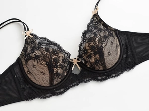 Gros plan sur le soutien-gorge en dentelle noire avec nœuds beiges et détails en mesh