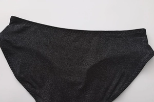 Dettaglio del tessuto nero glitterato e delle cuciture rifinite per slip a vita bassa