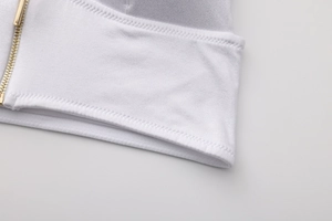 Vista macro del reggiseno a triangolo bianco con cerniera frontale dorata e finitura liscia