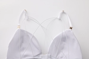 Dettaglio del bralette a triangolo bianco con spalline sottili e fibbie in metallo dorato