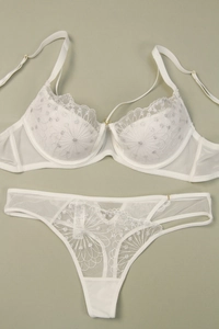 Close-up of white lace embroidery with silver thread and golden adjustment buckles