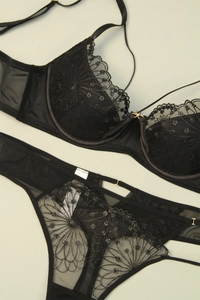 Detailed macro view of black lace embroidery and metallic accents on this bra set