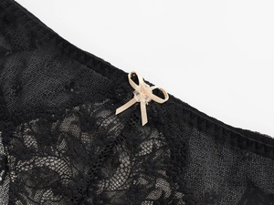 Détails macro de dentelle florale noire et nœud en satin sur une culotte taille basse