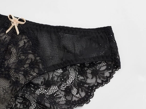 Détail de sous-vêtement en dentelle florale noire avec mesh transparent et nœud beige